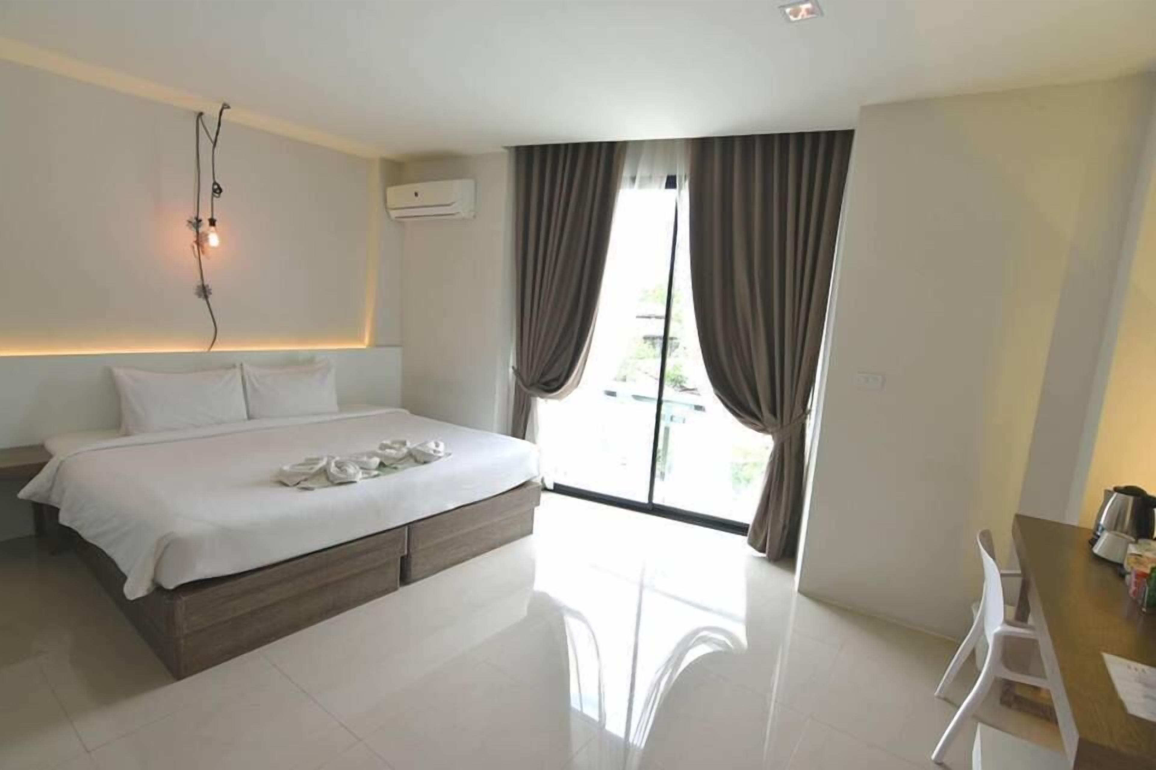 A modern hotel room with a large bed, a desk, and a view of the outdoors.
