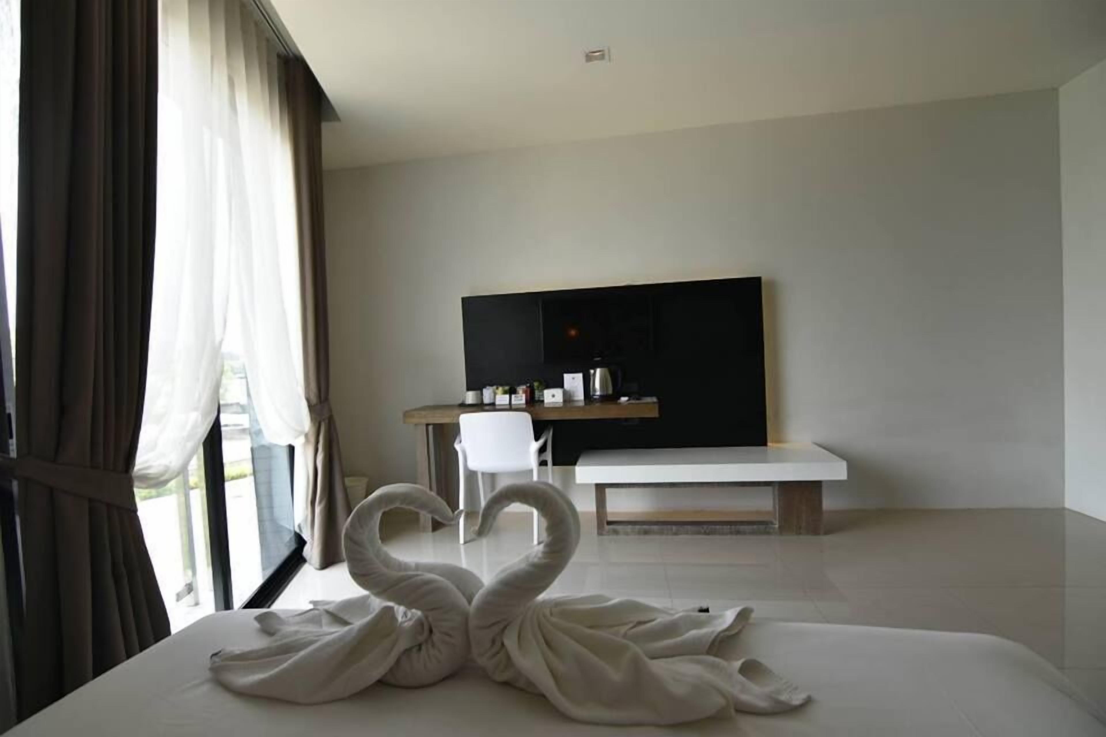 Una habitación de hotel moderna con una cama, un televisor, un escritorio y una ventana con cortinas.
