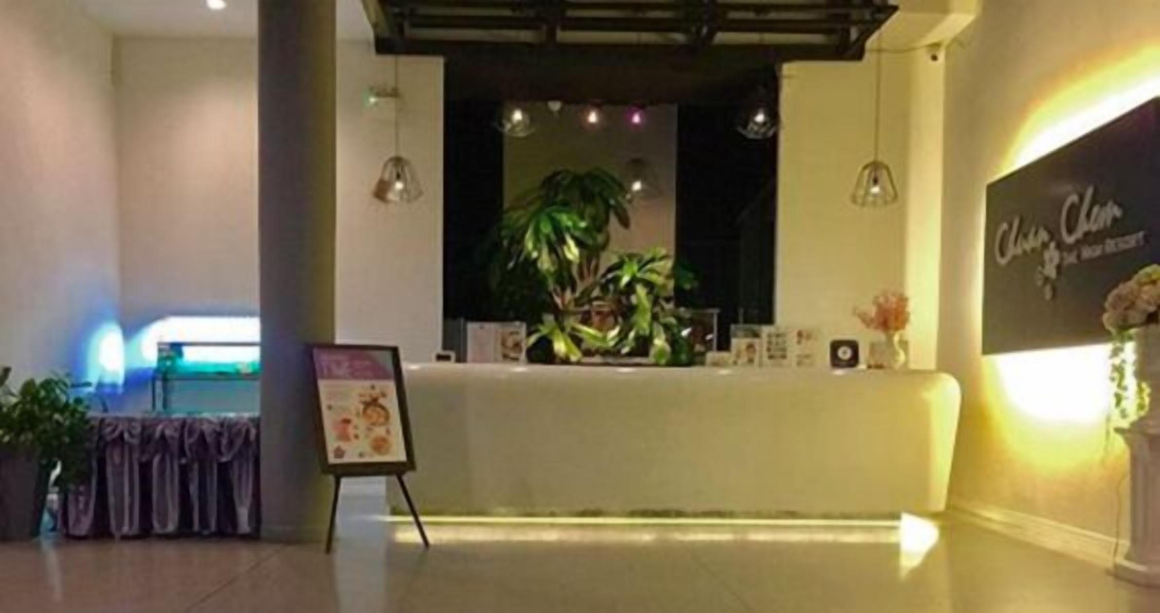 A reception area with a reception desk, a potted plant, and a signboard.