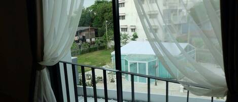 A balcony with a view of a residential area, including a house and a green structure.
