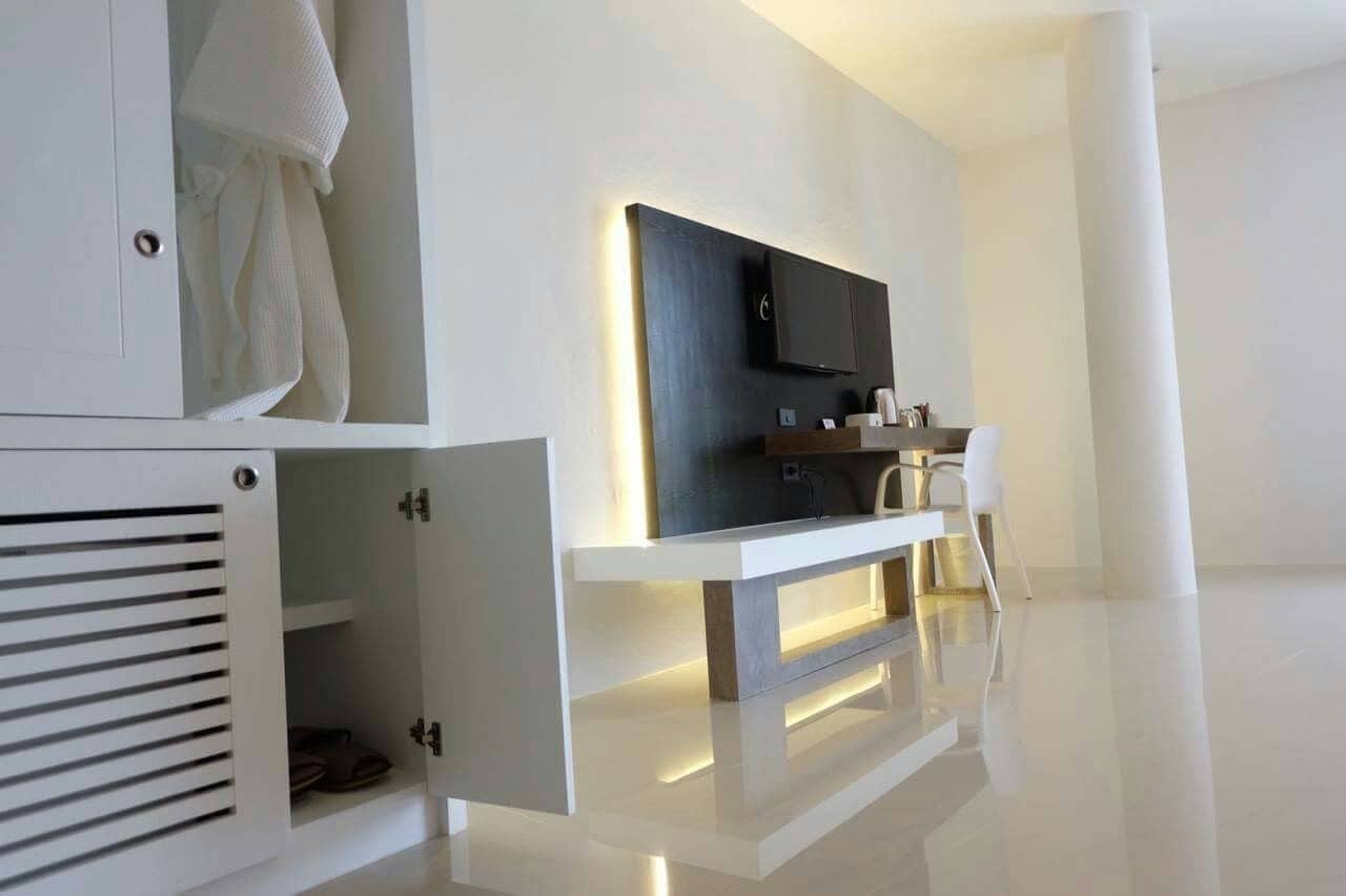 Een moderne, minimalistische kamer met een ingebouwde televisie, een witte console tafel en een stoel.