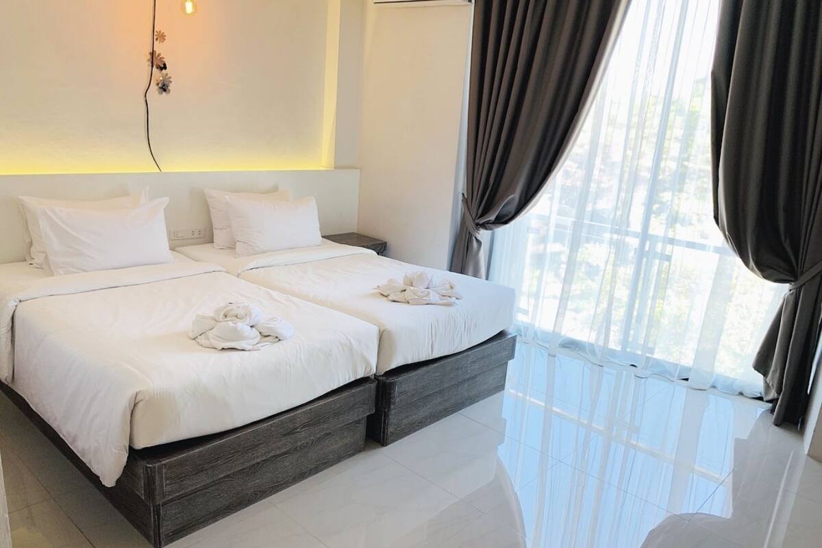 Una habitación de hotel moderna con una cama grande, una mesita de noche y vistas al exterior.