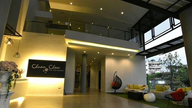A spacious lobby with a sign reading "Chuan Clean The High Resort," a modern seating area with cushions, and a balcony overlooking the outdoor space.