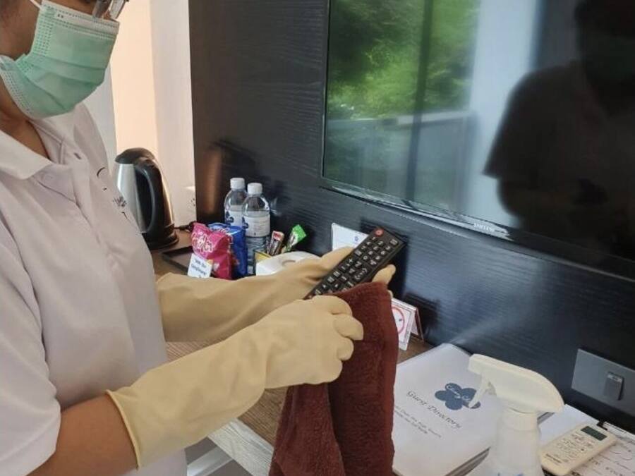 A person cleaning a TV screen with a cloth and a spray bottle.