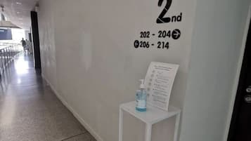 Un pasillo con un letrero que indica 'Floor 2nd' y números de habitación '202-204' y '206-214'. También se observa una pequeña mesa con una botella de agua y un letrero.