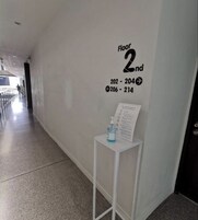 Un pasillo con un letrero que indica 'Floor 2nd' y números de habitación '202-204' y '206-214'. También se observa una pequeña mesa con una botella de agua y un letrero.