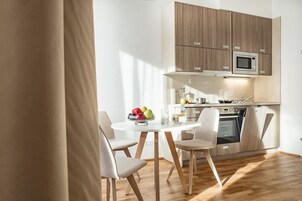 Una cocina moderna con armarios de madera, microondas integrado y zona de comedor con una mesa redonda y sillas.