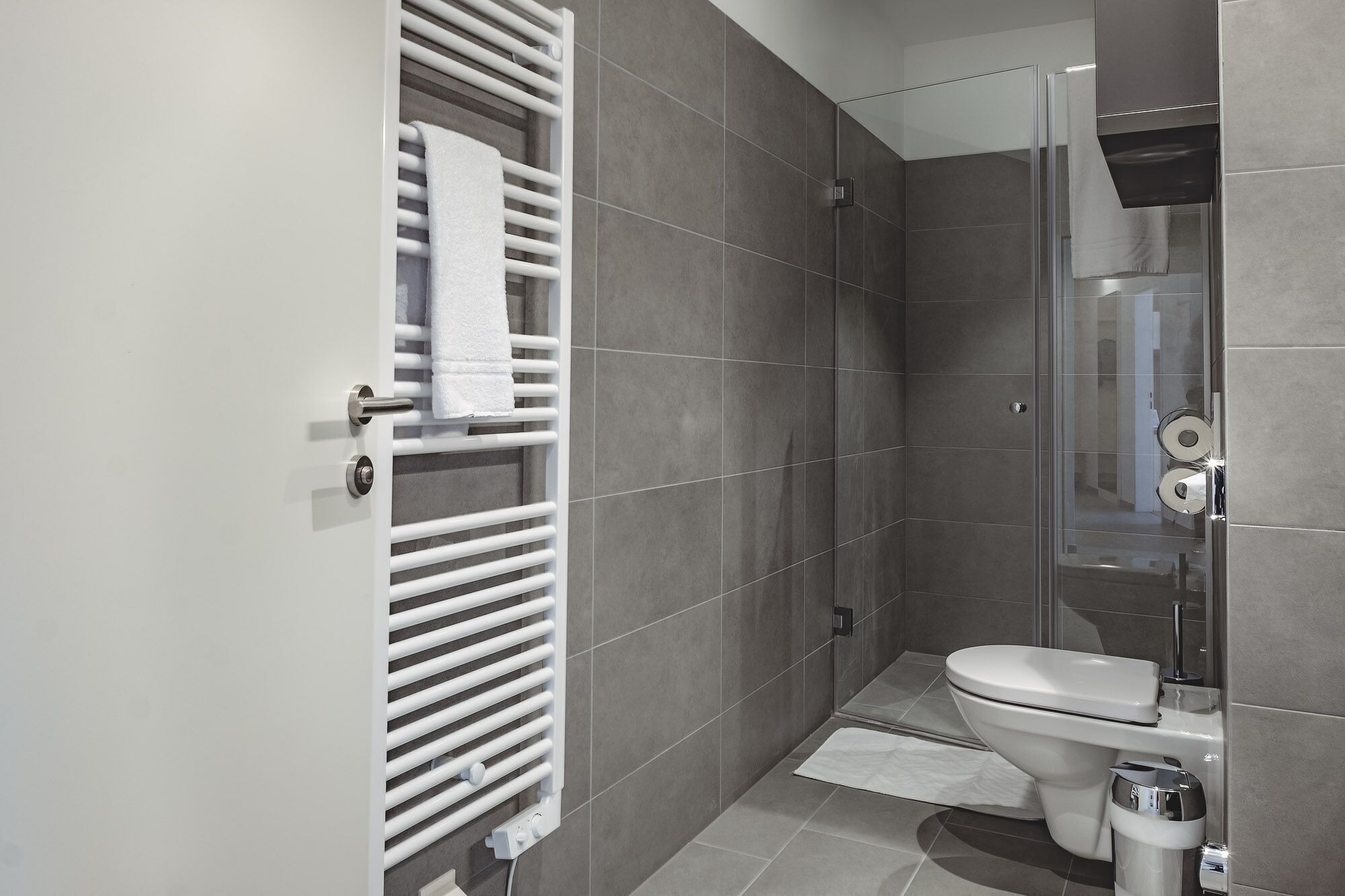 Un baño moderno con ducha, inodoro y barra para toallas.