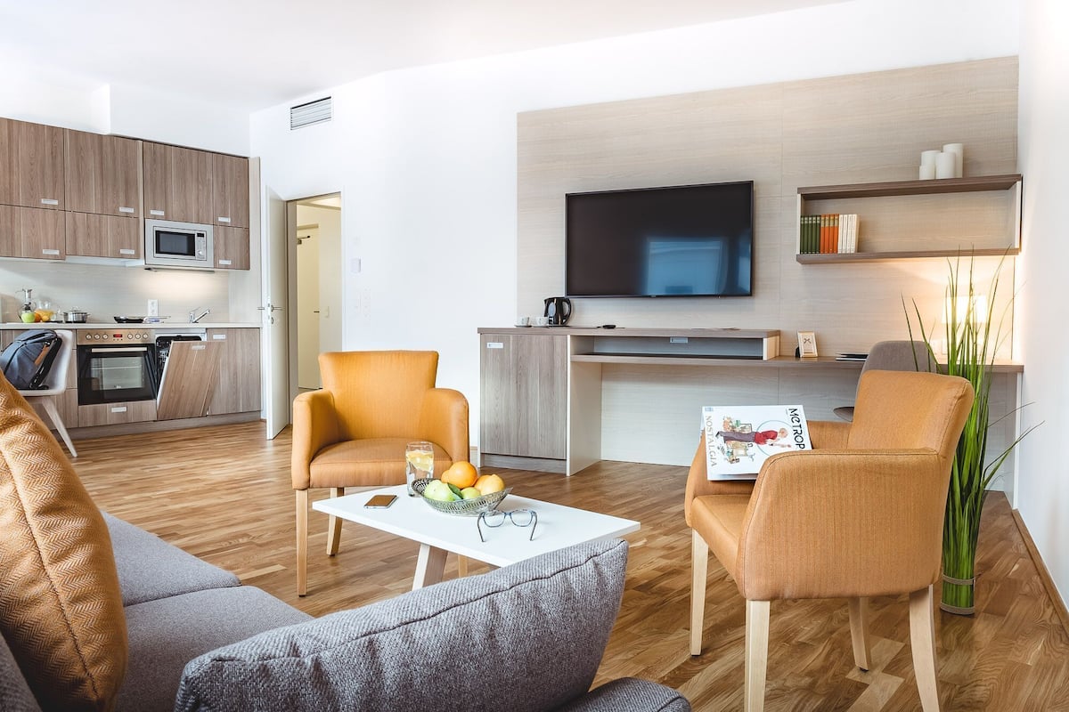 Uma sala de estar moderna com um sofá, poltronas, uma mesa de centro e uma televisão.