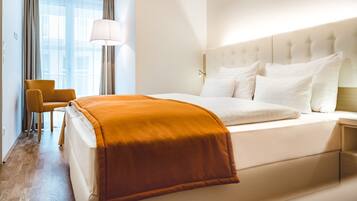 A hotel room with a large bed, a bedside lamp, a chair, and a view of the outdoors through the window.