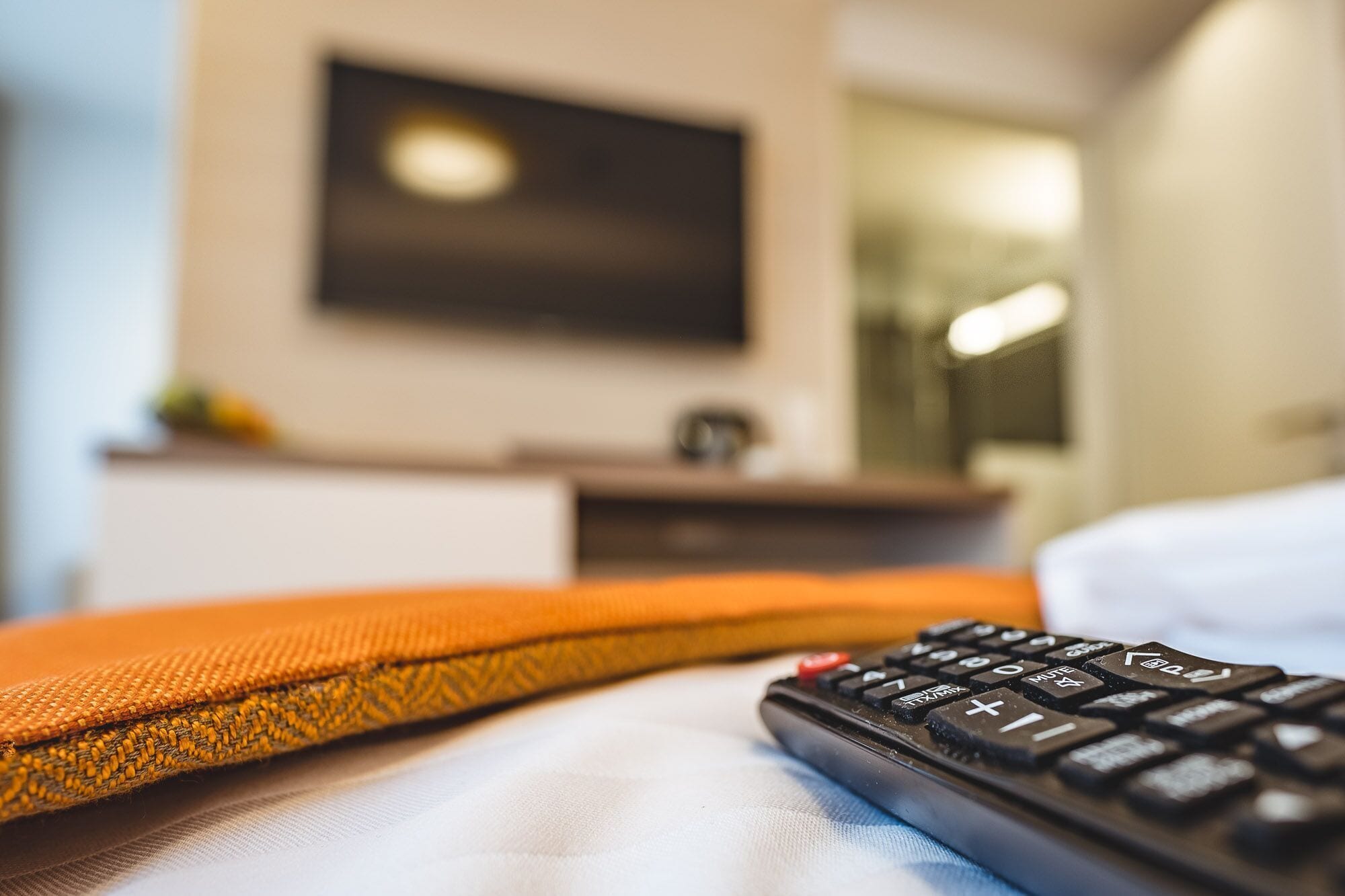 A bed with a remote control and a pillow.