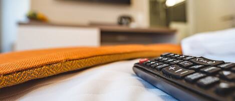 A bed with a remote control and a pillow.