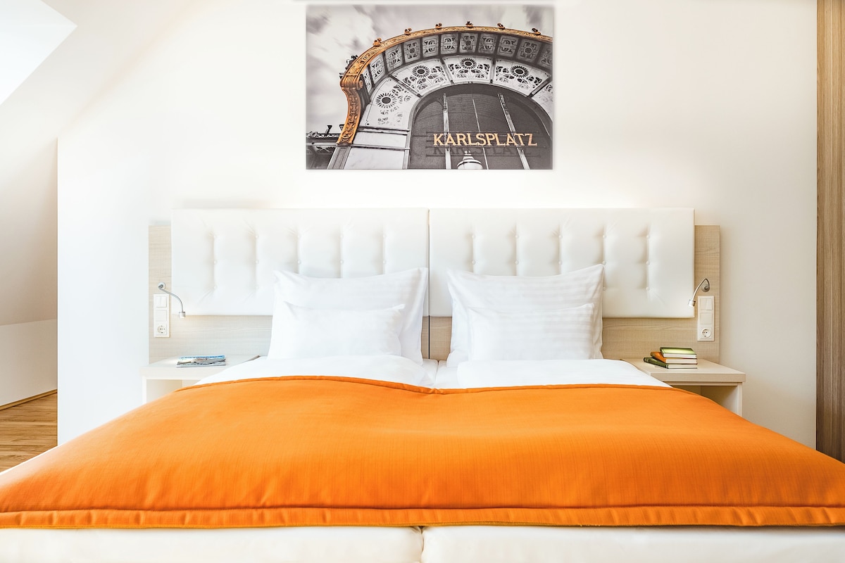 A hotel room with a bed, white headboard, two bedside tables, and a framed picture on the wall.