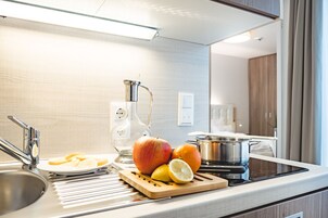 Una cucina moderna con lavello in acciaio inossidabile, un dispenser d'acqua in vetro, un tagliere con frutta e un fornello.
