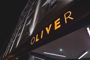 Un cartello con la scritta illuminata "OLIVER" di colore arancione.