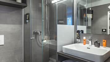 A modern bathroom with a glass-enclosed shower, a white sink, and a mirror.