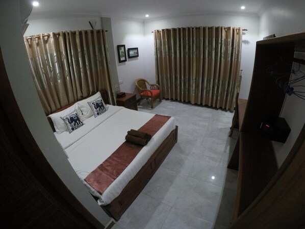 A hotel room with a bed, a chair, a desk, and a wardrobe. - Happy Family (Kampot)