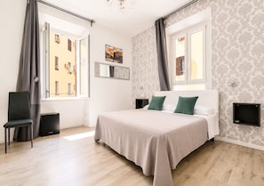 Een hotelkamer met een bed, een stoel, een tafeltje en een raam met gordijnen.