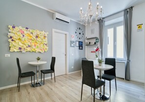 A modern dining area with a chandelier, a wall clock, and a bulletin board with notes. - Inside Roma Rooms by DOT Suites (Rome)