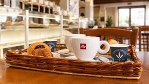 A breakfast setting with croissants, coffee cups, and a wicker tray on a table. - Inside Roma Rooms by DOT Suites (Rome)