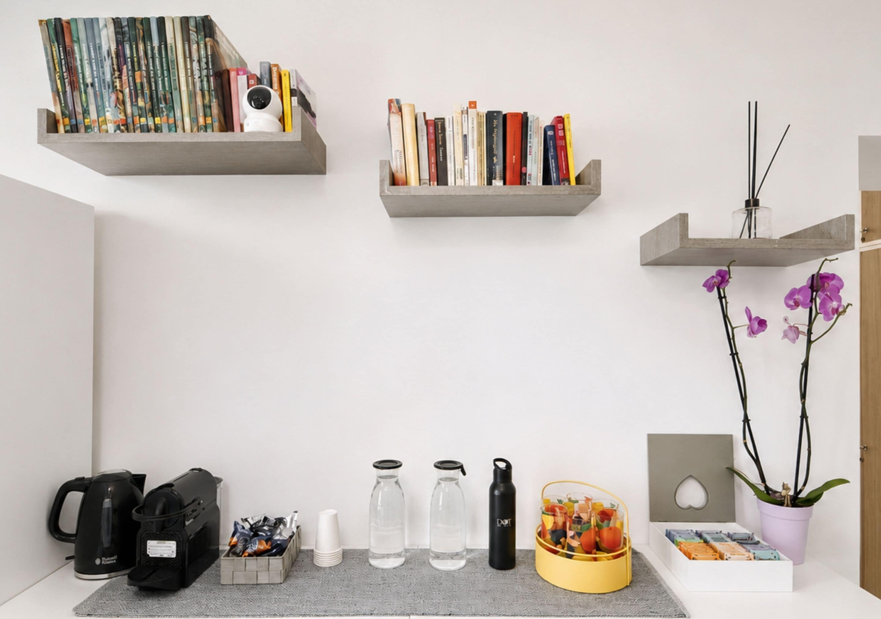 A workspace with shelves holding books, a camera, and a potted orchid.