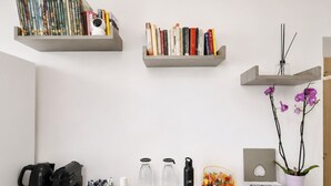 A workspace with shelves holding books, a camera, and a potted orchid. - Inside Roma Rooms by DOT Suites (Rome)