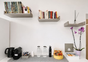 A workspace with shelves holding books, a camera, and a potted orchid. - Inside Roma Rooms by DOT Suites (Rome)