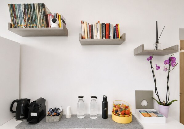 A workspace with shelves holding books, a camera, and a potted orchid. - Inside Roma Rooms by DOT Suites (Rome)