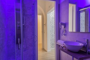 A modern bathroom with a glass-enclosed shower, a large vessel sink, and a mirror above the sink. - Inside Roma Rooms by DOT Suites (Rome)
