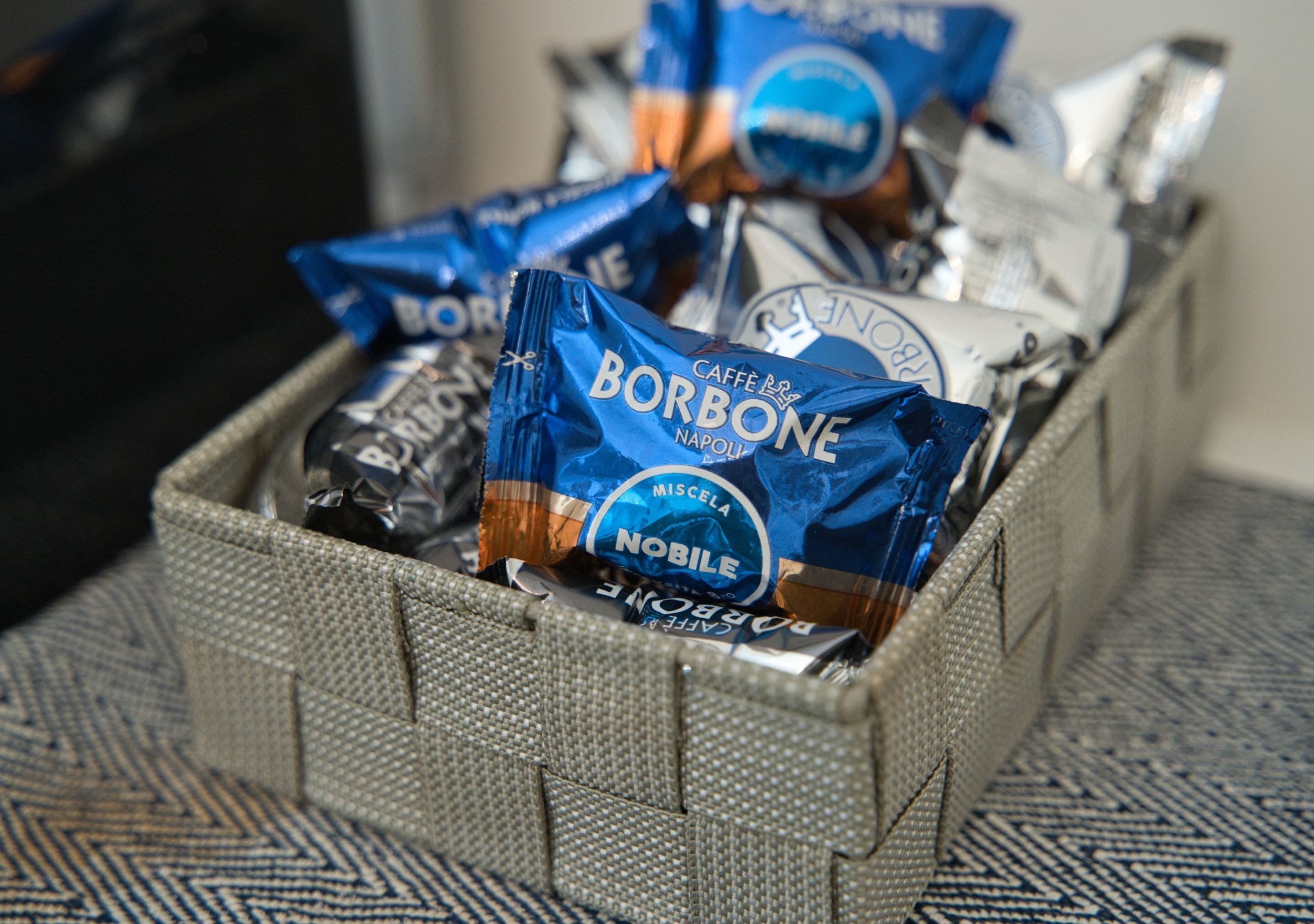 A storage bin filled with various packaged items, including a prominent Borbone brand chocolate.