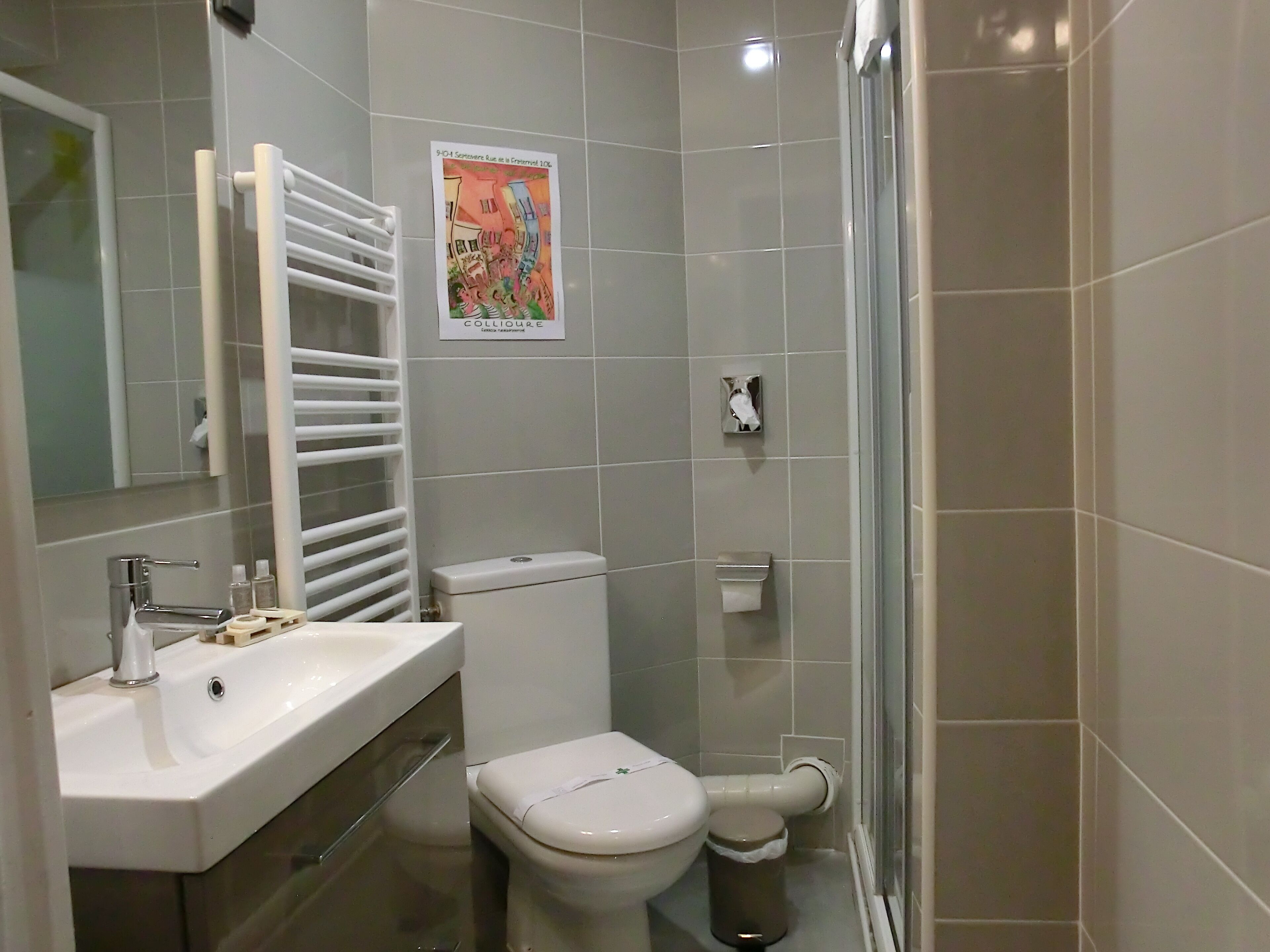 A bathroom with a white sink, toilet, and a glass shower enclosure.
