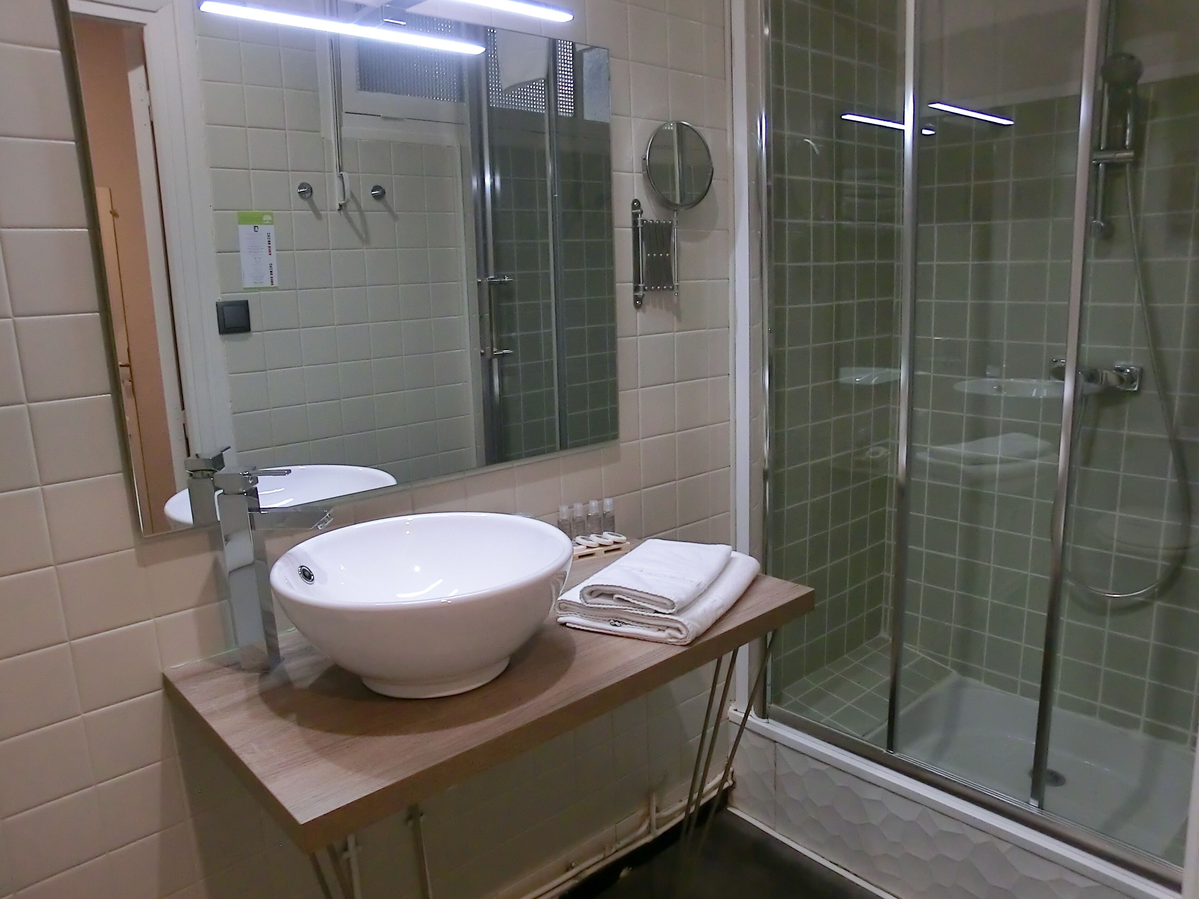A bathroom with a white sink, mirror, and glass-enclosed shower.