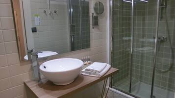 A bathroom with a white sink, mirror, and glass-enclosed shower.