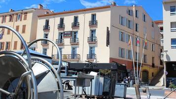 A hotel with balconies, a sign indicating a restaurant, and a view of the street.