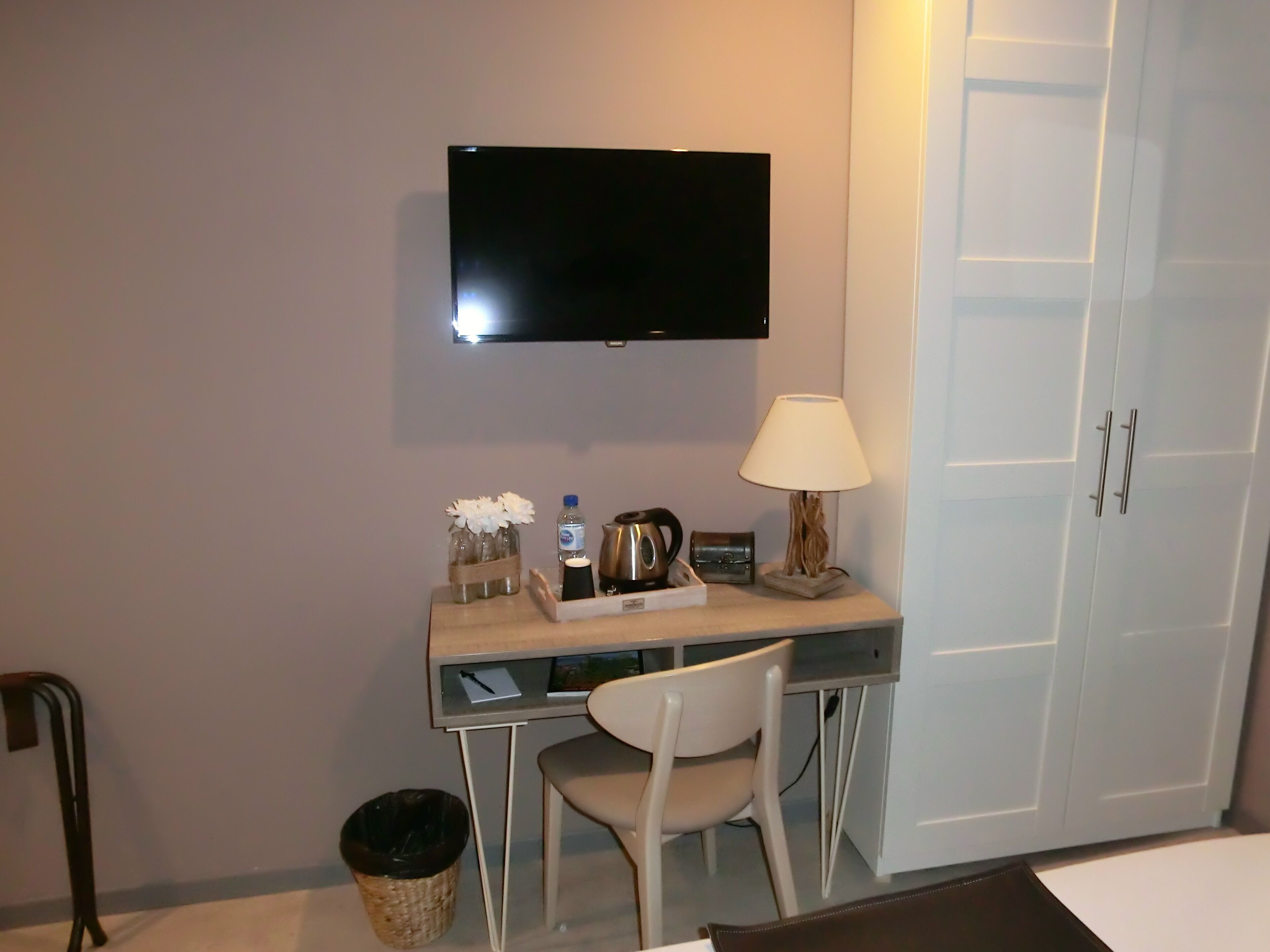 Une chambre d’hôtel équipée d’un bureau, d’une chaise, d’une télévision, d’une lampe et d’une armoire.