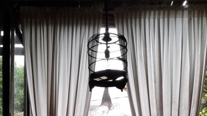 A spa area with a large bathtub, a thatched roof structure, and a view through curtains. - Rustic Hut in Seminyak Bali (Seminyak)