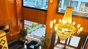 A hotel lobby with a modern design, featuring a large chandelier, leather seating, and a patterned floor. - Spor Hotel (Ankara)
