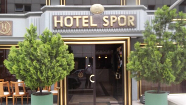 The exterior of Hotel Spor with a modern entrance, two potted trees, and a seating area with chairs. - Spor Hotel (Ankara)