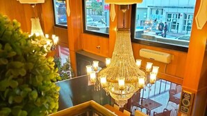 A hotel lobby with a grand chandelier, wooden decor, and a view of the street outside. - Spor Hotel (Ankara)