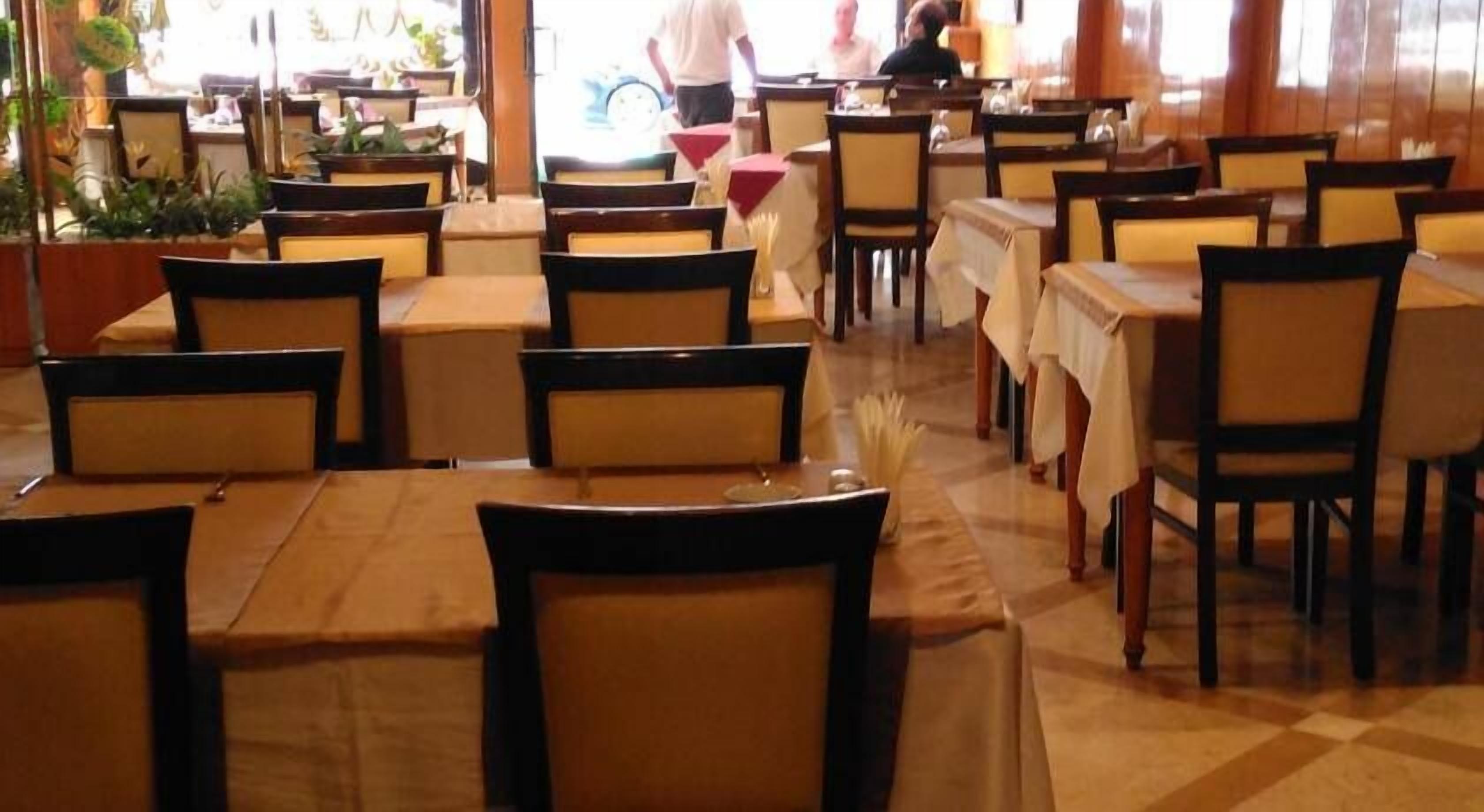 A restaurant with multiple tables and chairs, some with tablecloths.