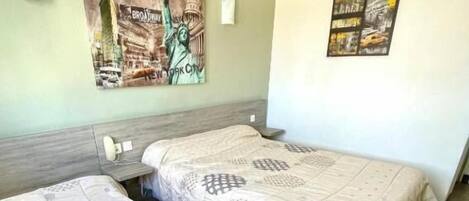 A hotel room with two beds, a green wall, and two posters.