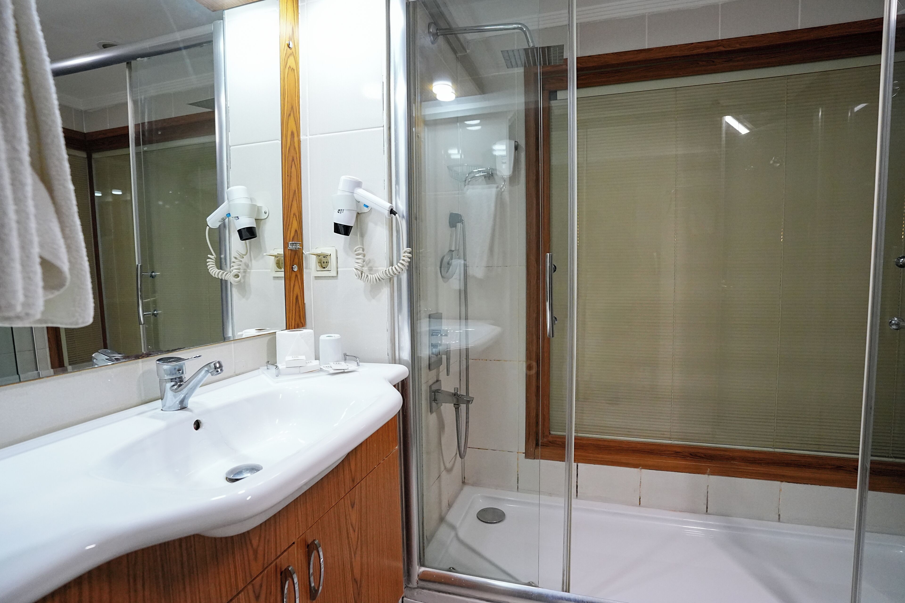 A bathroom with a glass-enclosed shower, a white sink, and a wooden vanity.