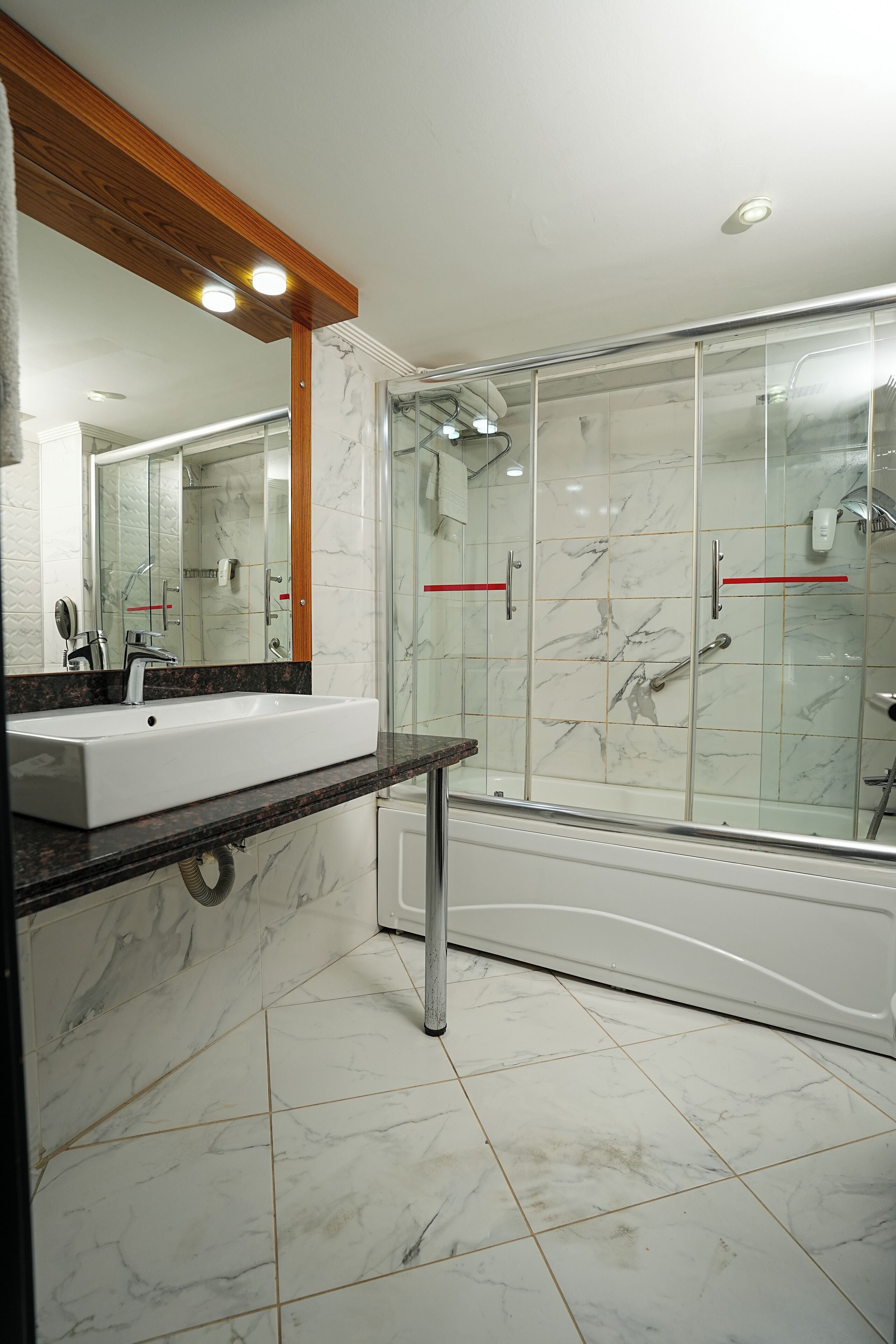 Een moderne badkamer met een marmeren wastafel, een douchecabine van glas en een bad.
