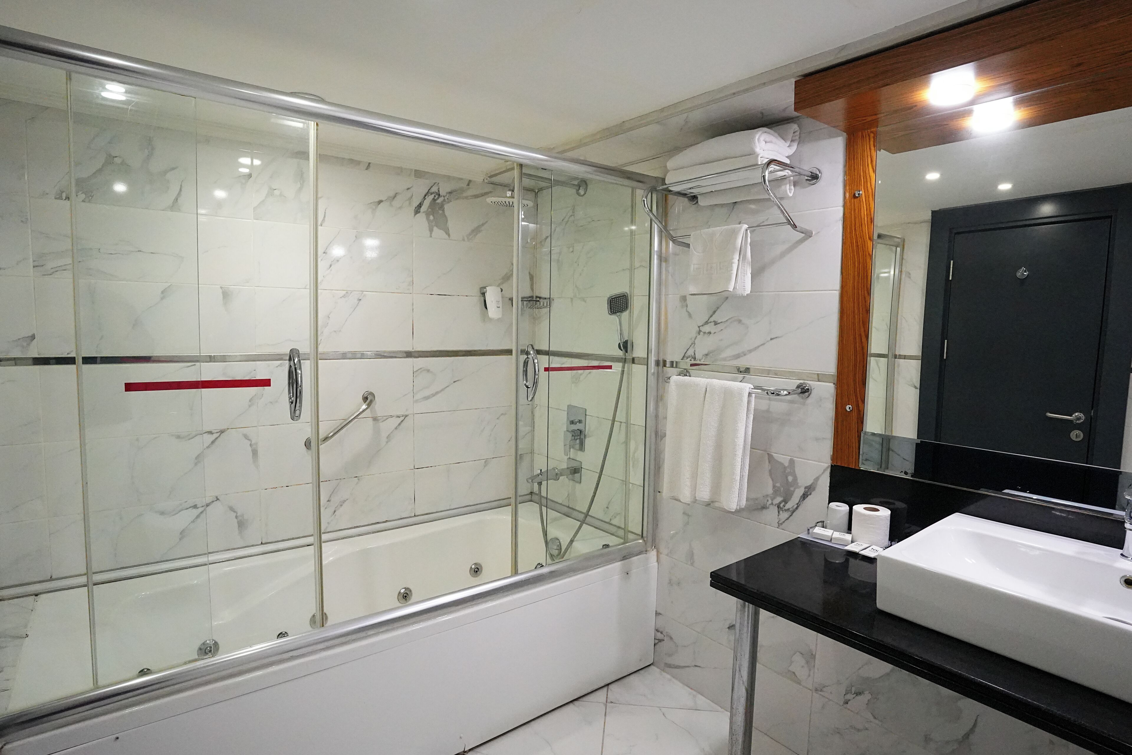 Une salle de bain moderne avec une douche à parois de verre, une baignoire, un lavabo et un miroir.