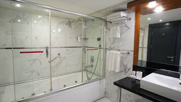 Une salle de bain moderne avec une douche à parois de verre, une baignoire, un lavabo et un miroir.