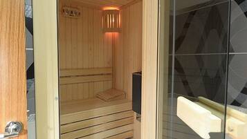 A sauna with wooden benches and a glass door.
