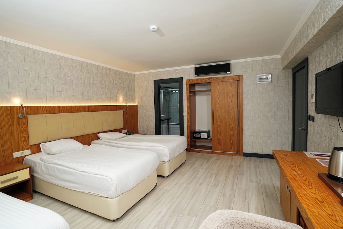 A hotel room with two beds, a wooden headboard, a TV, a wooden desk, and a mirror.