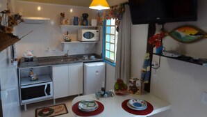 Une cuisine compacte équipée d’un four à micro-ondes, d’un évier et d’un coin repas agrémenté de sets de table rouges.