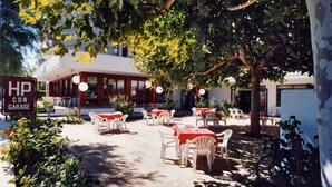 Un patio al aire libre con mesas y sillas, una zona de estar cubierta y un letrero que indica un garaje.