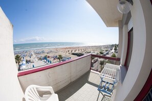 A balcony with a view of a beach, a table, and chairs. - Palmarosa (Roseto degli Abruzzi)